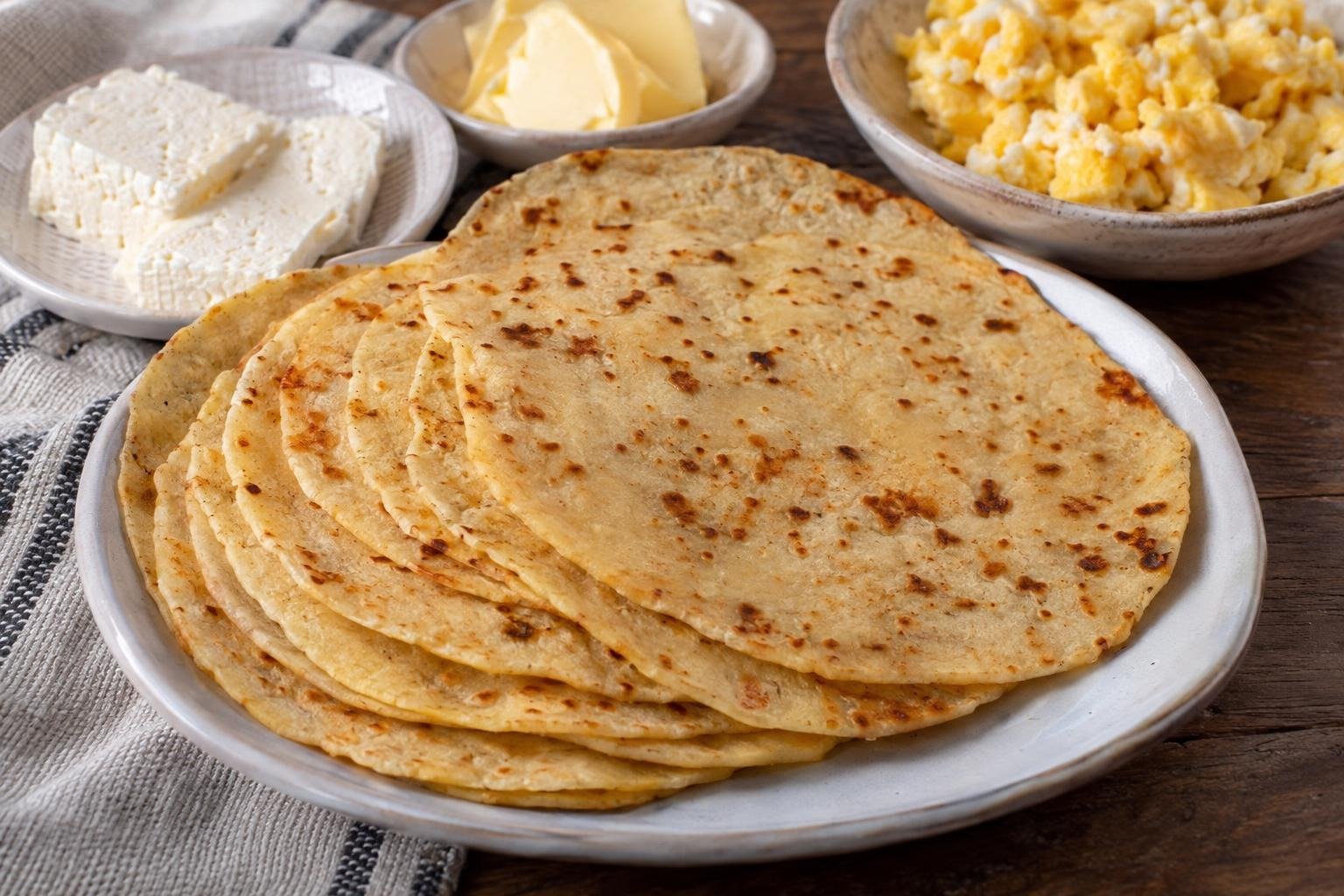 Arepas oreja de perro huilenses muy delgadas y ligeramente doradas, servidas con queso fresco, mantequilla y huevos.