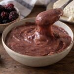 Arequipe de mora colombiano cremoso servido en un cuenco con moras, queso fresco y obleas