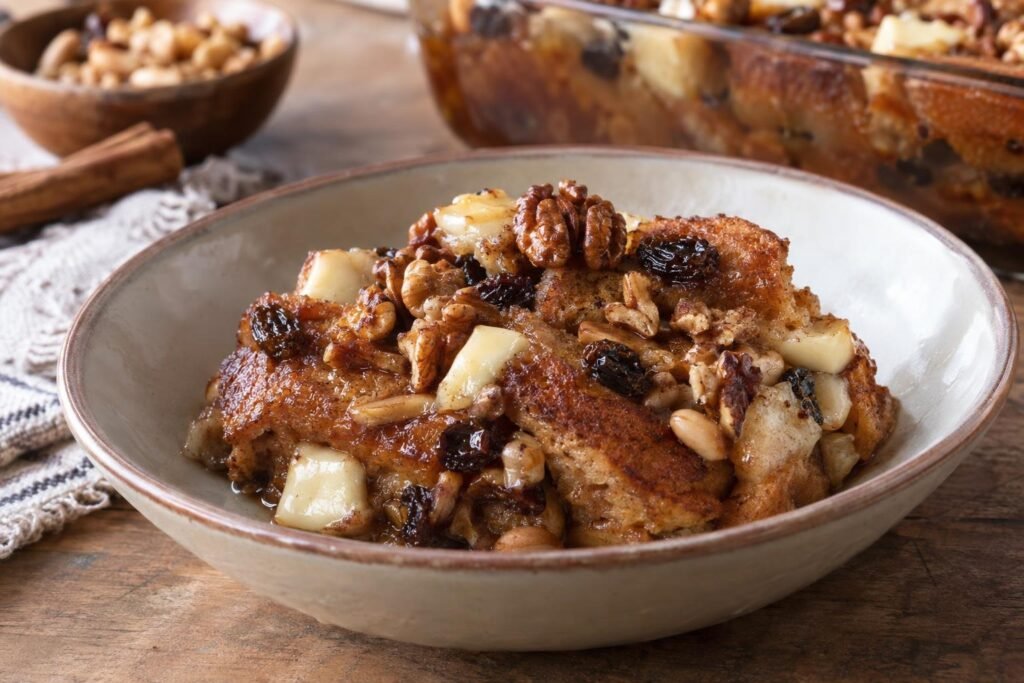 Porción de capirotada mexicana con pan dorado, piloncillo, pasas, cacahuates, nueces y queso en capas