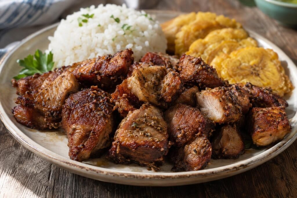 Trozos dorados de carne frita puertorriqueña de cerdo servidos con arroz blanco y tostones
