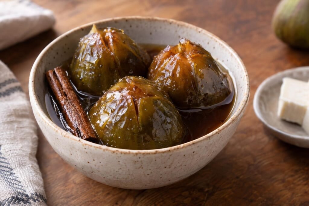 Dulce de brevas colombianas enteras en almíbar brillante de panela, servido con una rama de canela y queso fresco.