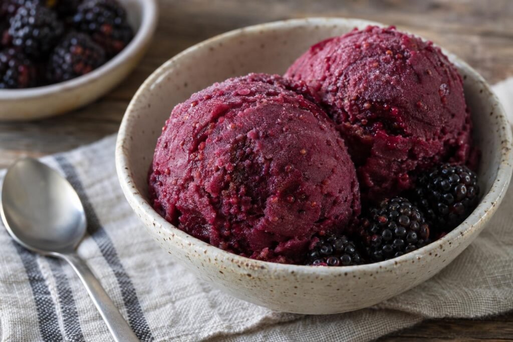 Dos porciones de helado de paila nariñense de mora, morado intenso y con algunas semillas visibles, servidas en un cuenco.