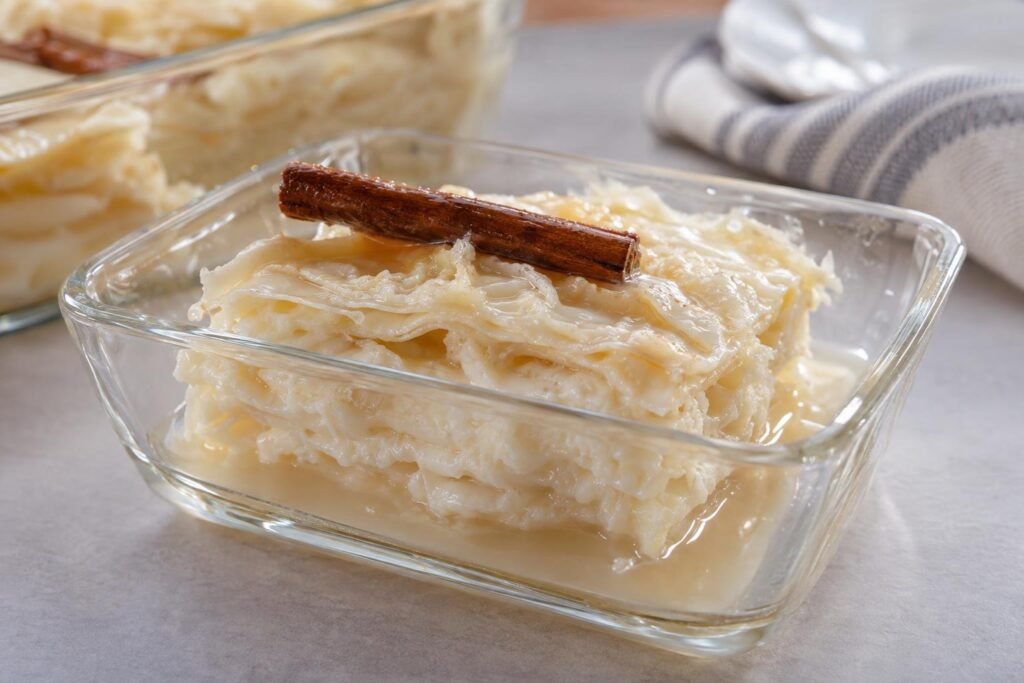 Porción de postre de natas colombiano con capas blancas de leche y almíbar claro de canela servido en una fuente de vidrio.