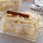 Porción de postre de natas colombiano con capas blancas de leche y almíbar claro de canela servido en una fuente de vidrio.
