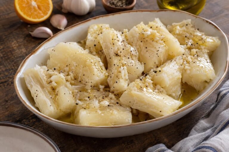 Trozos tiernos de yuca hervida cubiertos con mojo cubano de ajo, aceite y naranja agria en una fuente